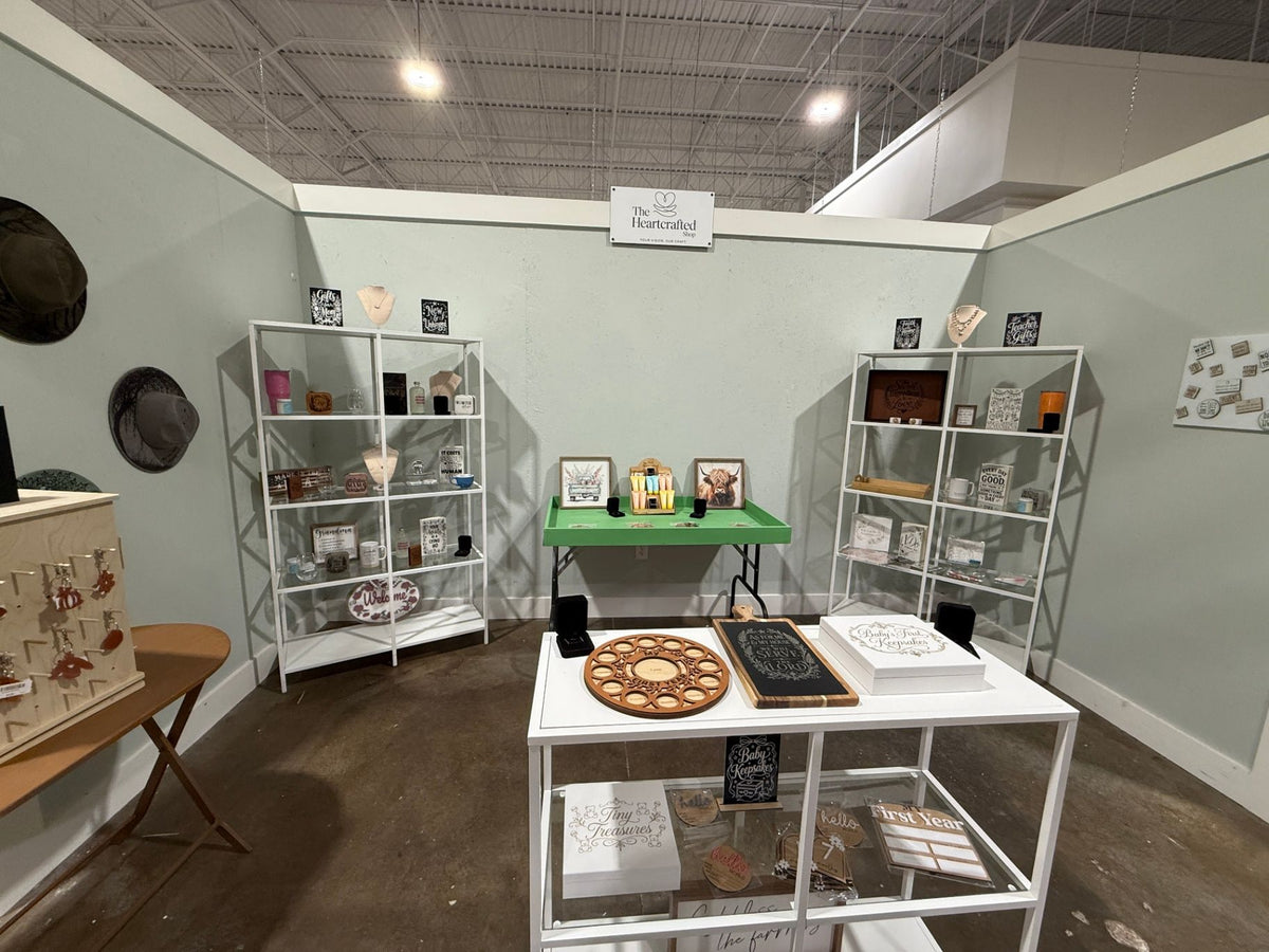 The Heartcrafted Shop booth at The Collective Boutique Cinco Ranch with white shelving, a display table, jewelry stands, engr